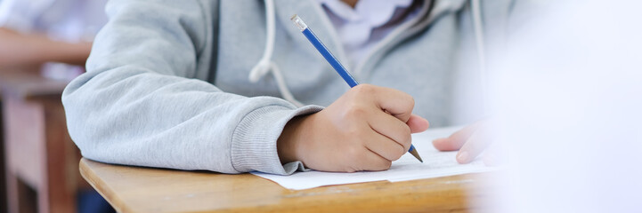 Close up hand of students reading and taking exam sheets exercises answer with stress in classroom