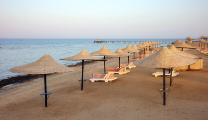 Beach with sun loungers and umbrellas at sunset, Marsa Alam region, Egypt.