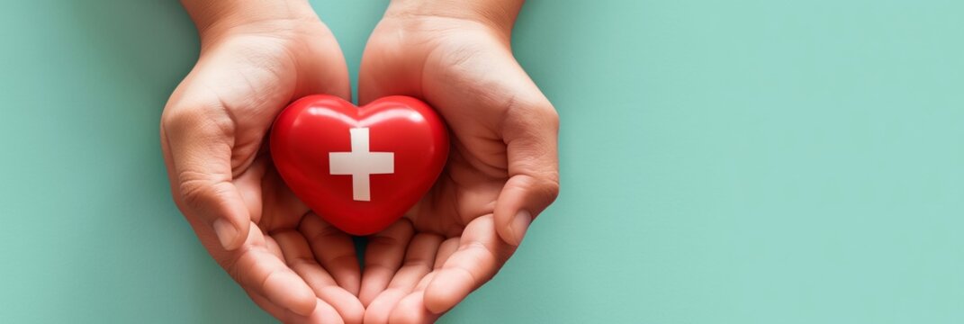 Two hands cradling a red heart with a white cross on a teal background, symbolizing healthcare and support
