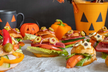 Monster sandwich made with olives, salami, tomato, lettuce, bun bread for Halloween. Kid's food ideas for Halloween