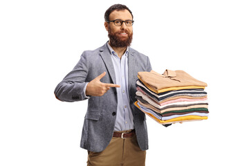 Bearded man pointing at a pile of folded clothes and smiling at camera