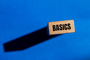 Basics word written on wooden block with blue background. Conceptual basics word symbol. Copy space.