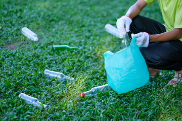 Close up picking up water bottles of trash, cleaning up school yards and recycling plastic.  Volunteer kid wearing gloves for safety, hot summer holiday.