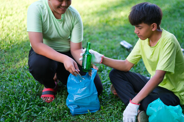 Teenagers picking up water bottles of trash cleaning up school yards and recycling plastic.  Volunteer Asian kid wearing gloves for safety, hot summer holiday.