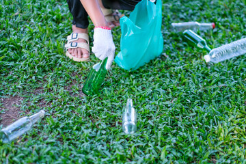 Close up picking up water bottles of trash, cleaning up school yards and recycling plastic.  Volunteer kid wearing gloves for safety, hot summer holiday.