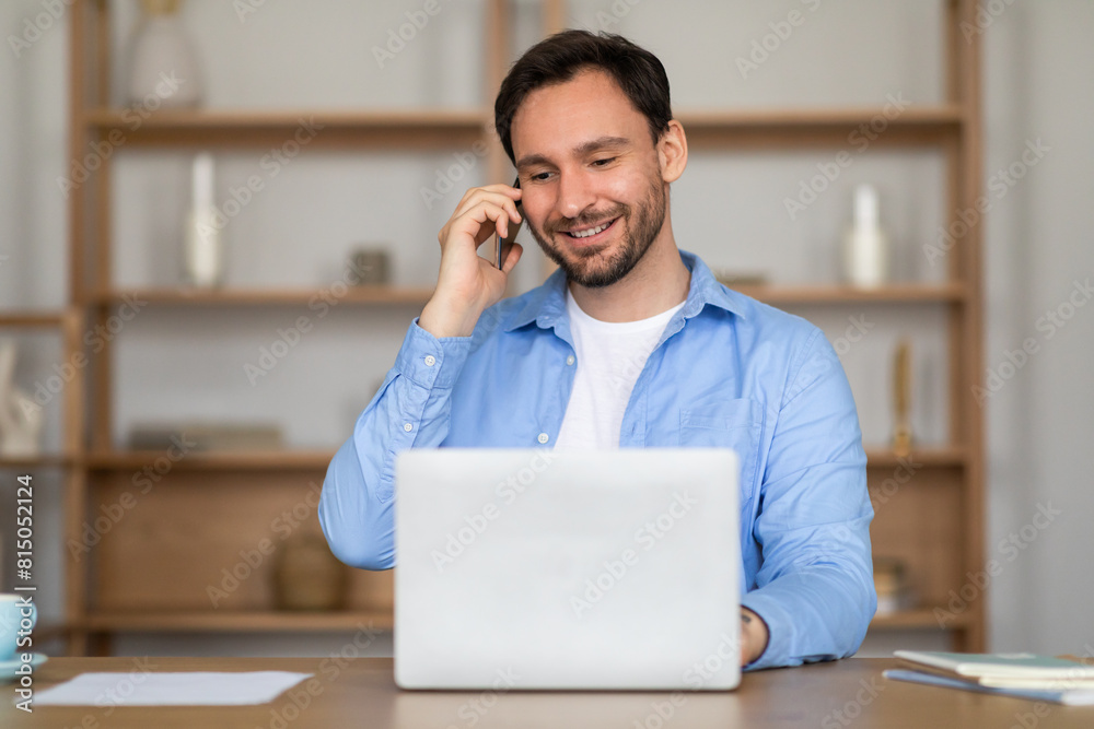 Aufkleber A man is sitting in front of a laptop, engaged in a phone call. He appears focused as he communicates on the phone while working on his computer.
