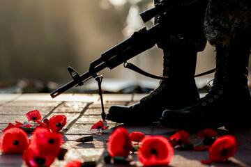 Memorial Day image featuring a simple silhouette of a soldier's rifle and boots with red poppies.