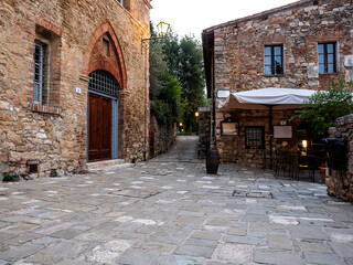 Medieval alleys with stone houses and a tent on a bar table at dawn in a tiny village in Tuscany
