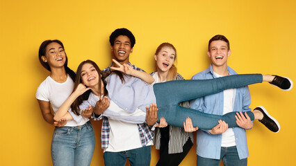 A diverse group of teenagers is seen gathering together and striking various poses in front of a...