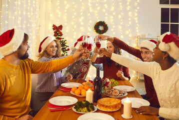 Group of cheerful young multiracial friends celebrate Christmas in cozy home atmosphere. People in...