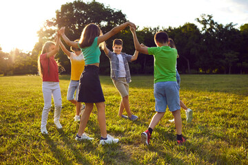 Friendly kids boys and girls hold hands standing in circle doing outdoor activities together...