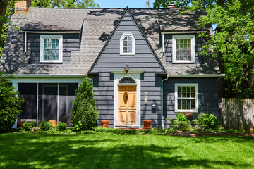 Traditional Two-Story Gray House with Lush Lawn and Terracotta Pots