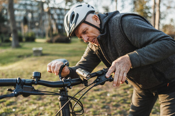 Senior Cyclist Checking the Handlebars of His Bicycle Before Riding