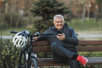 Man Sitting on Bench Next to Bicycle and Using Cell Phone