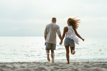 A Man and a Woman Running on a Beach Holding Hands
