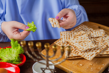 A Jewish woman eats matzo and bitter greens at the Pesach Seder table