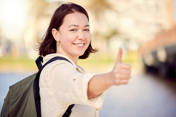 Portrait, tourist or happy woman in city with thumbs up for travel, good news or like for hiking on street road. Positive, hand gesture or girl with thank you smile, yes sign or vote for okay review