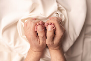 Baby feet of a newborn in dad's hands. On a white background.