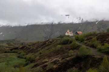 Gudauri, Georgia in cloudy weather with green grass and snow on montains pics in May. View on ...