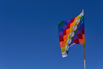 wiphala symbol flag flying on a background of clear blue sky in Humahuaca, Argentina.