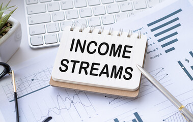 INCOME STREAMS text written on the white background with keyboard, paper sheet and pen.