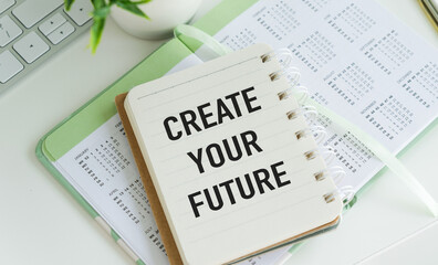 Holding white notebook sign with Create Your Future text message on white wall office background.