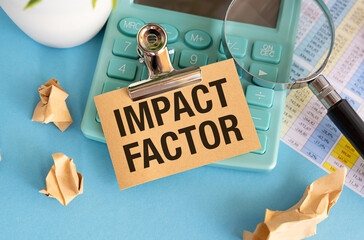 Impact Factor text on paper clipboard with chart and notebook on blue background
