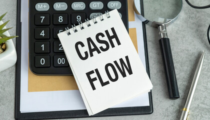 Cash flow text concept on notebook with office tools and paper.Business concept