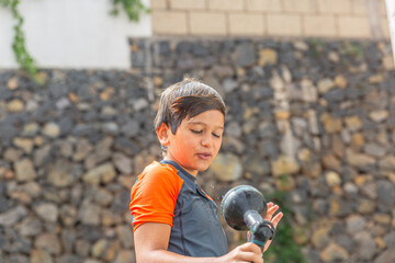 A content child smiles as he plays with a garden hose, water droplets suspended around him in a...