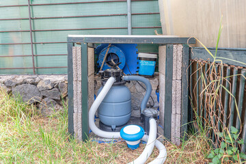 Pool filtration system with pump, filter, and hoses in a home backyard setting.