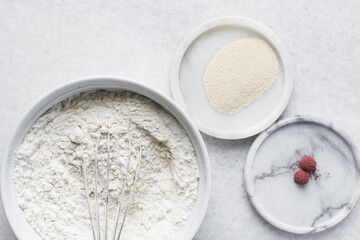 Mise en place of ingredients for making beet bread, All purpose flour beet powder and yeast on a marble countertop, process of making bread
