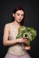 A captivating woman poses in a photo studio with an acacia branch.