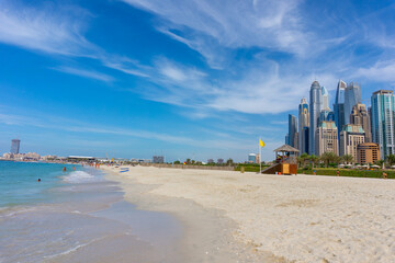 Dubai skyscraper skyline with palm trees and the sand of the beach with a rustic hut