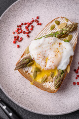 Delicious hearty breakfast consisting of poached eggs on toast with cream cheese, asparagus