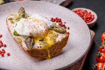 Delicious hearty breakfast consisting of poached eggs on toast with cream cheese, asparagus