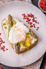 Delicious hearty breakfast consisting of poached eggs on toast with cream cheese, asparagus