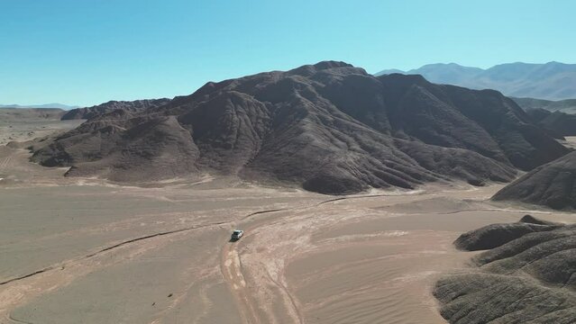 Traves&iacute;a en 4x4 a trav&eacute;s de paisaje monta&ntilde;oso &aacute;rido desolado inh&oacute;spito en una quebrada de la Puna Argentina visto desde drone. (4)