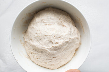 Bread dough that has doubled in size, dough that has risen, proofed dough in a white bowl
