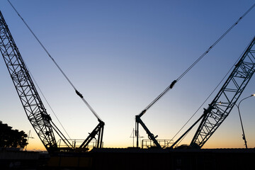 Two construction cranes diverging into morning sky