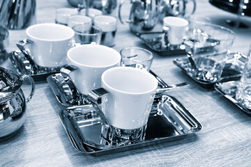 A table with a variety of cups and saucers, including a white cup with a handle