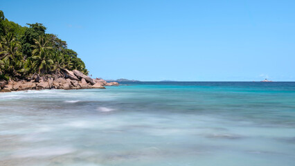 A beautiful blue ocean with a boat in the distance. The water is calm and the sky is clear, Seychelles Ladigue