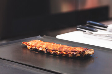 A piece of meat is on a grill, with the grill marks visible. The meat is brown and he is cooked. Concept of anticipation and excitement, as the meat is being prepared for consumption
