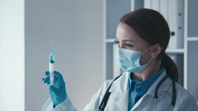 A healthcare worker holding a syringe with a vaccine prepares to vaccinate a patient, demonstrating responsibility for public health. The general practitioner inserts the syringe to provide treatment