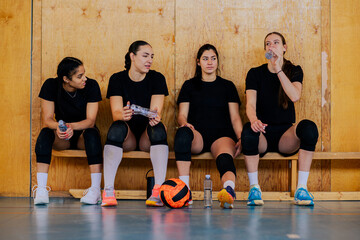 Woman volleyball players sitting on a bench after the match or a training