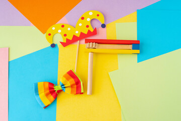 Jewish holiday Purim concept with traditional decorations noisemaker, clown bow tie on colorful...