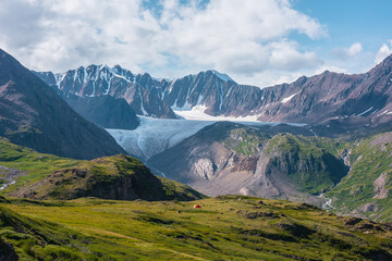 Colorful landscape with orange tent in alpine valley with view to big glacier tongue and large...