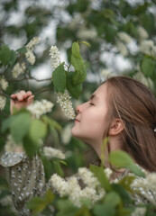 A photo of a beautiful girl near a flowering tree.