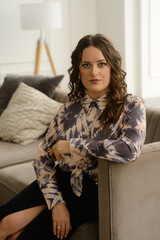 A psychologist girl in a business style poses in an interior photo studio.