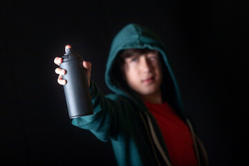 A young man holds a can of spray paint in his hand pointing to start his graffiti