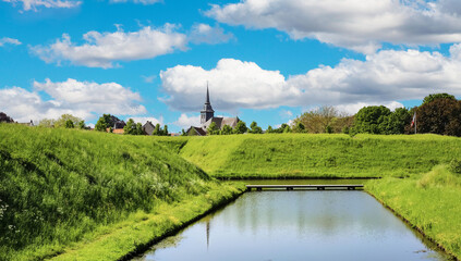 Medieval earth, green pasture and water wall of historical fortified village with church - Stevensweert, Netherlands